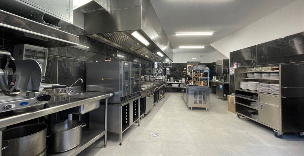 Intérieur d'une cuisine professionnelle de restauration rapide moderne avec plans de travail en inox propres et éclairage naturel abondant
